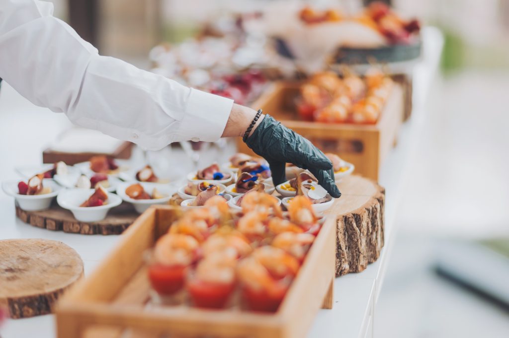 Hands,Of,A,Waiter,Prepare,Food,For,A,Buffet,Table